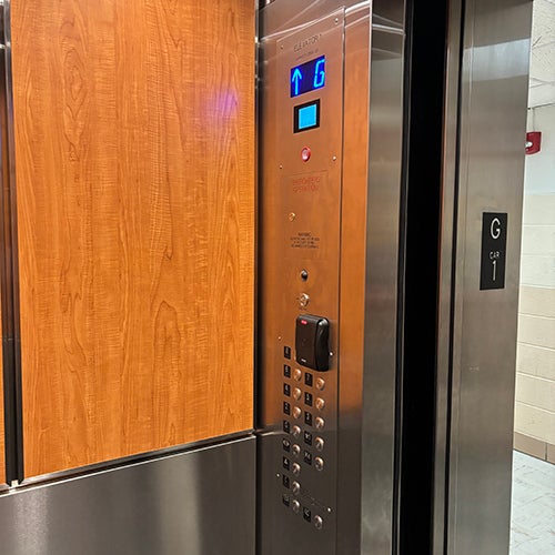 modernized elevator with a wood-grain-paneled door and a new stainless steel control panel.