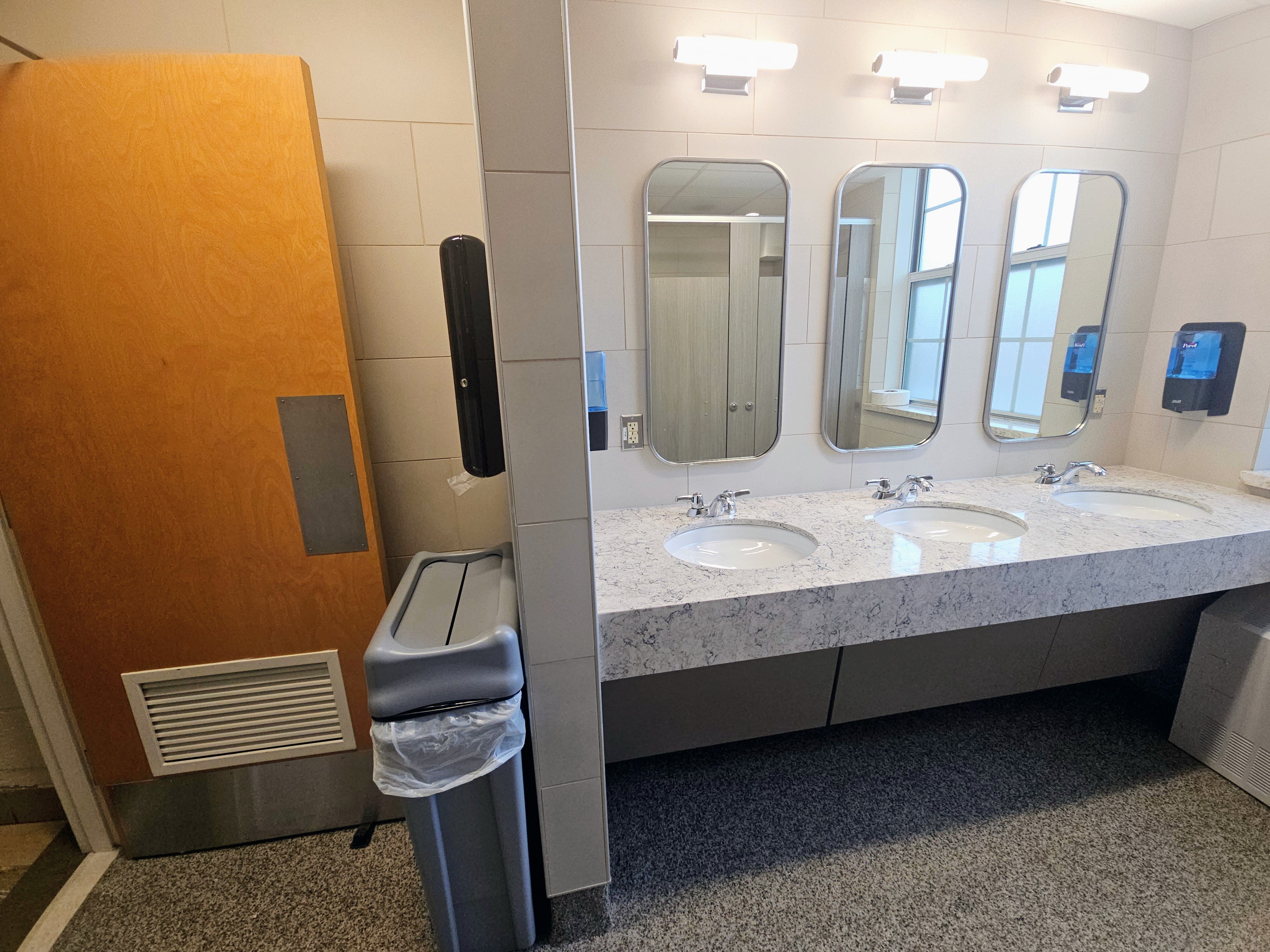 side view of bathroom showing the door, sinks and mirrors