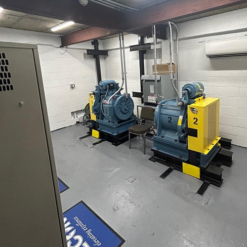 modernized machine room with two large, yellow and blue industrial machines and electrical cabinets.