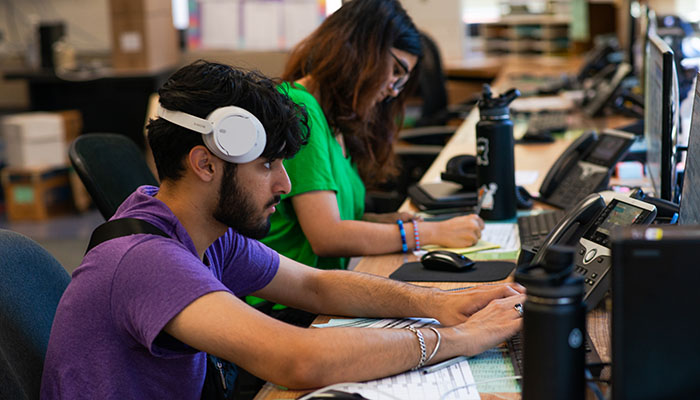 close up of two student employees working at a desk the Service Center