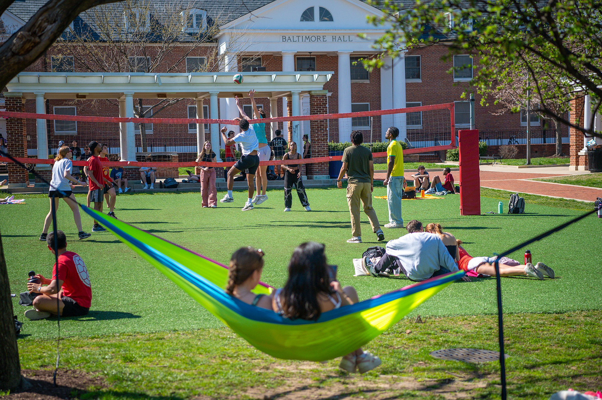 students in hammocks and playing volleyball on Washington Quad