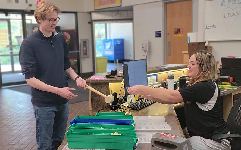 community assistant giving resident bed lofting materials at the service desk