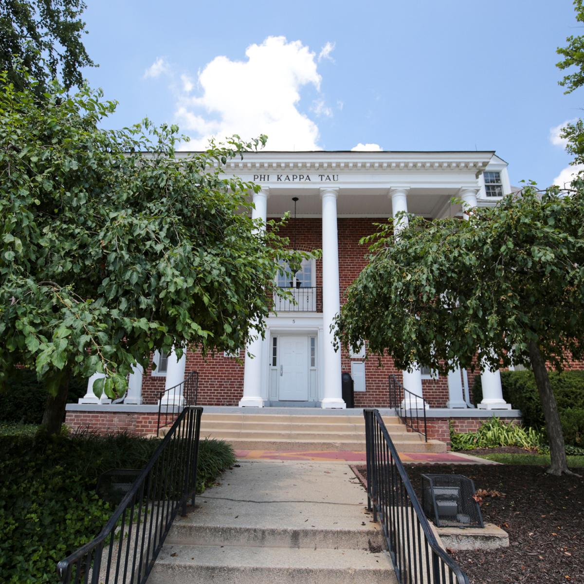 Brick house at 5 Fraternity Row with white columns and surrounding greenery