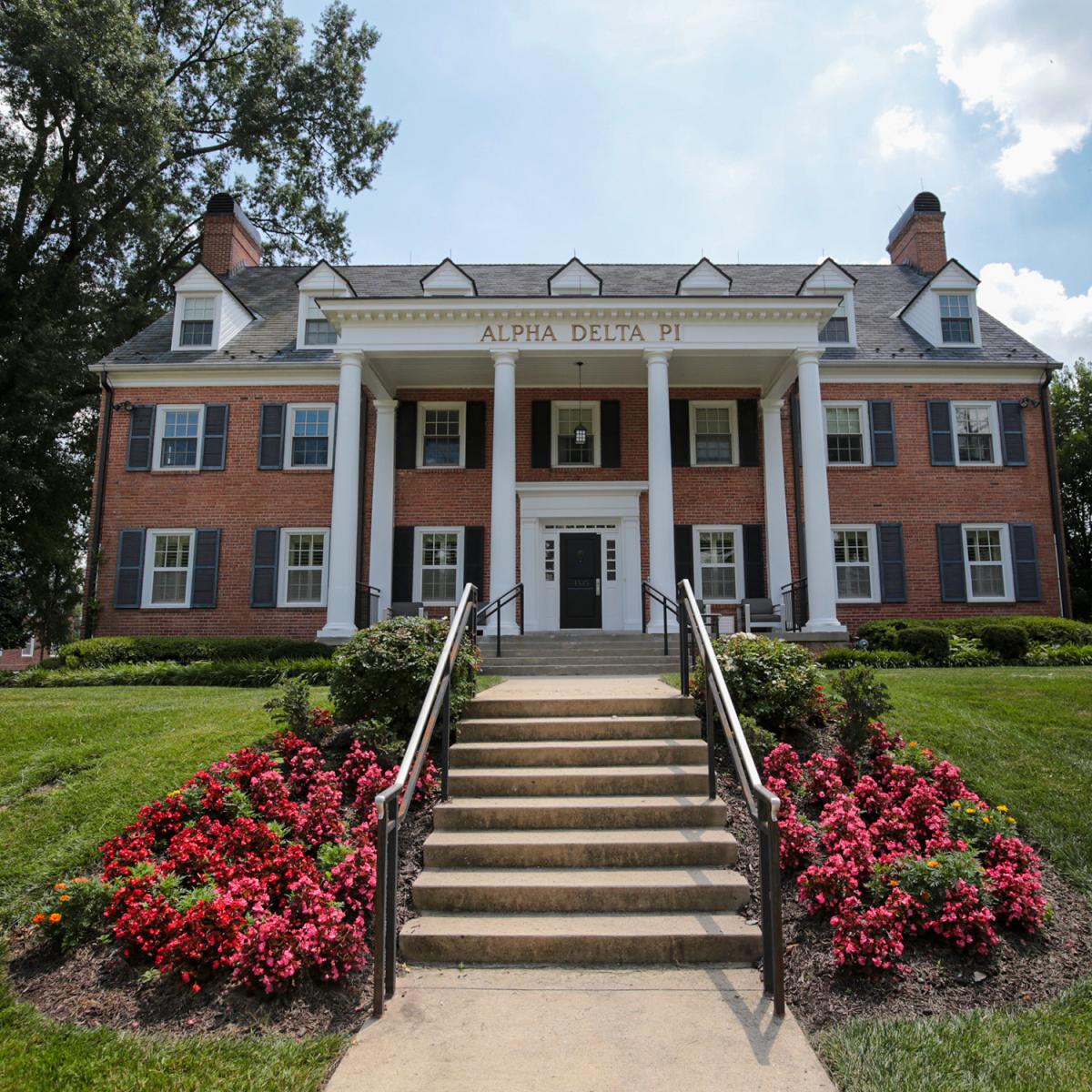 Brick house at 4535 College Avenue with window shutters, white columns, and a front entrance framed by surrounding greenery