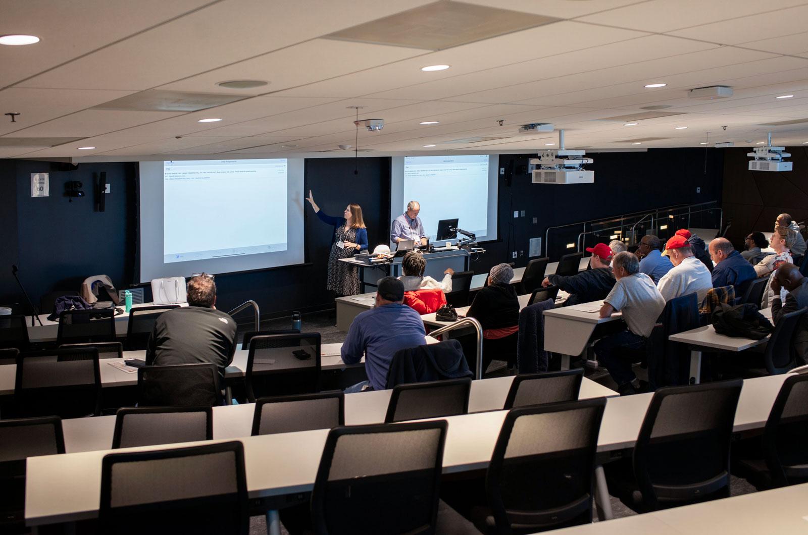 View from back of auditorium with Kelly Ridings & Patrick Rhodes presenting at the front