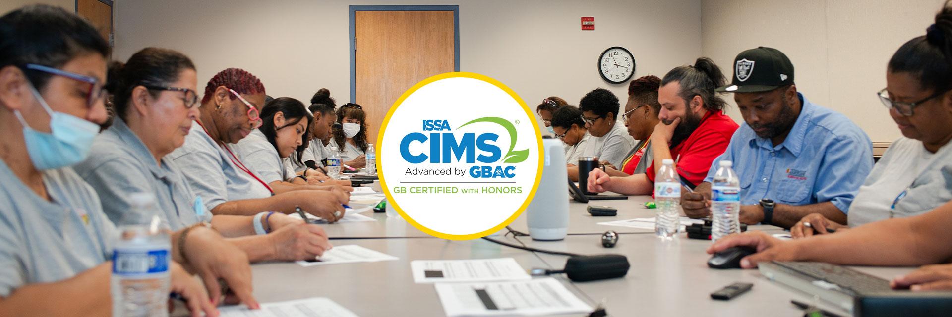 Housekeeping staff around conference table with CIMS certification logo in the center