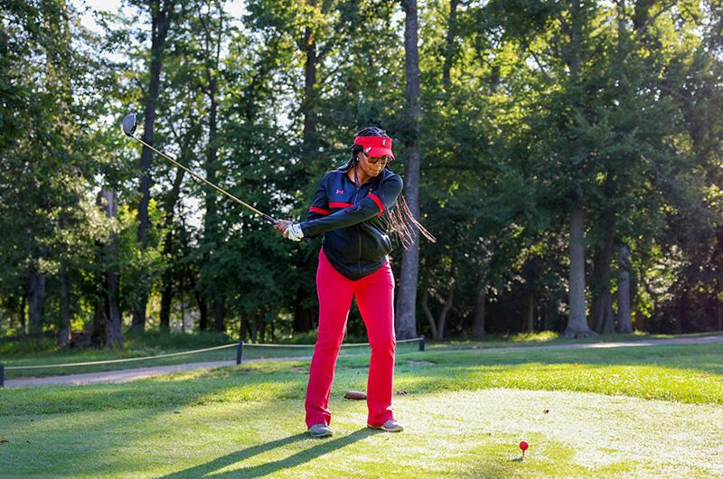 woman swinging a club at a ball on the golf course 