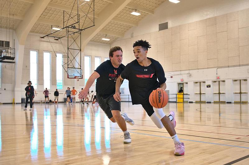 two students playing basketball at Reckord Armory