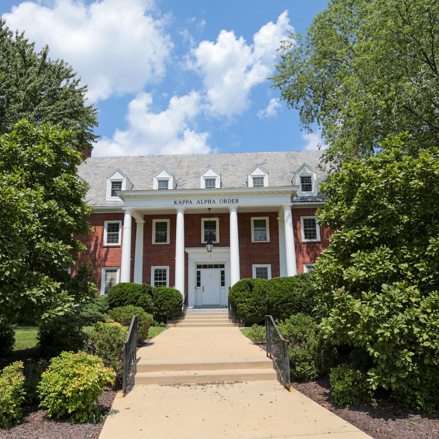 Brick house at 1 Fraternity Row with white columns and surrounding greenery