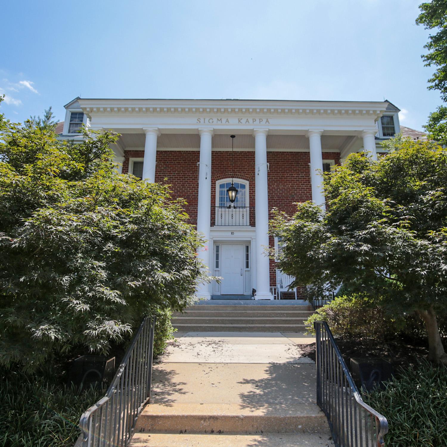 Brick house at 10 Fraternity Row with white columns and surrounding greenery