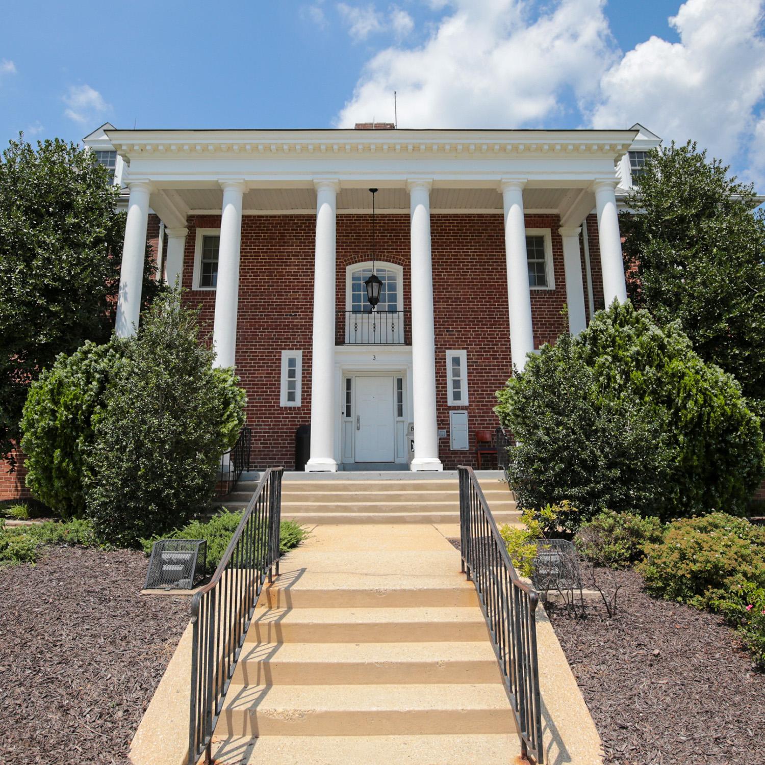 Brick house at 3 Fraternity Row with white columns and surrounding greenery