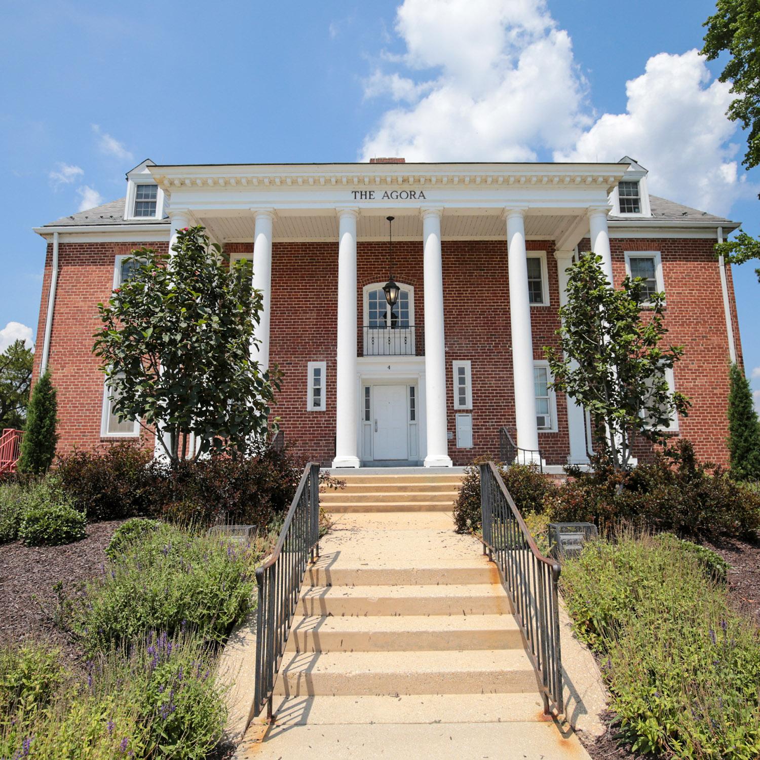 Brick house at 4 Fraternity Row with white columns and surrounding greenery