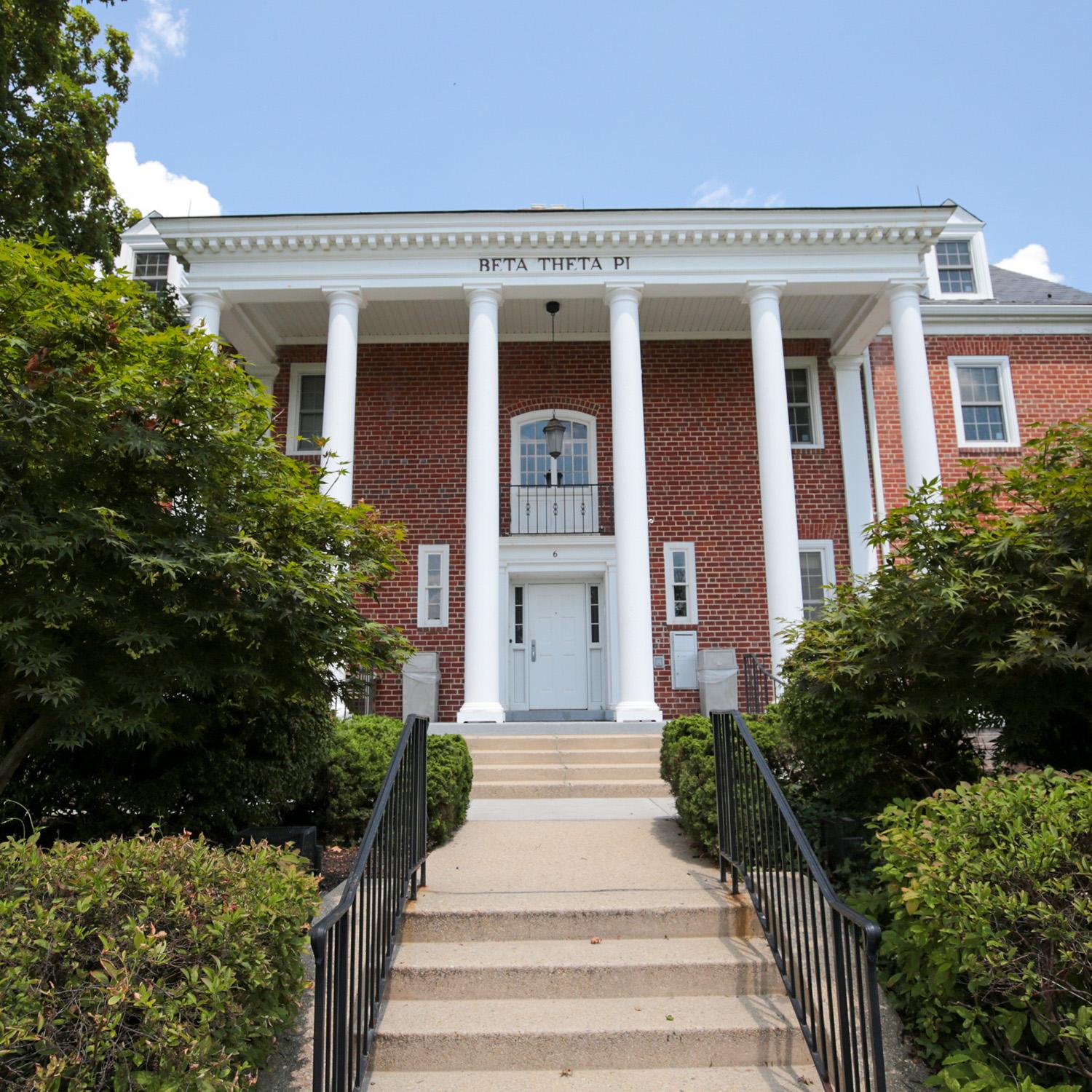 Brick house at 6 Fraternity Row with white columns and surrounding greenery