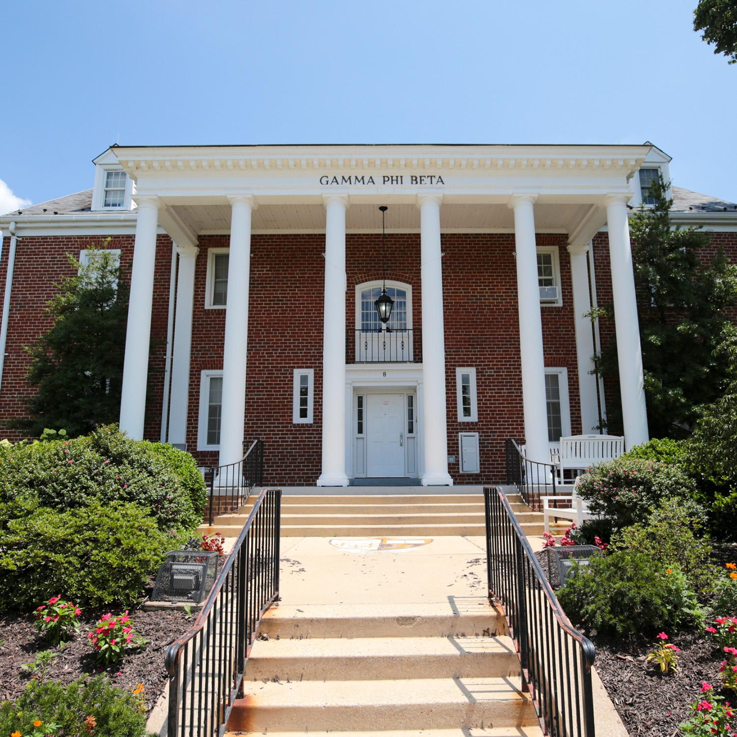 Brick house at 8 Fraternity Row with white columns and surrounding greenery