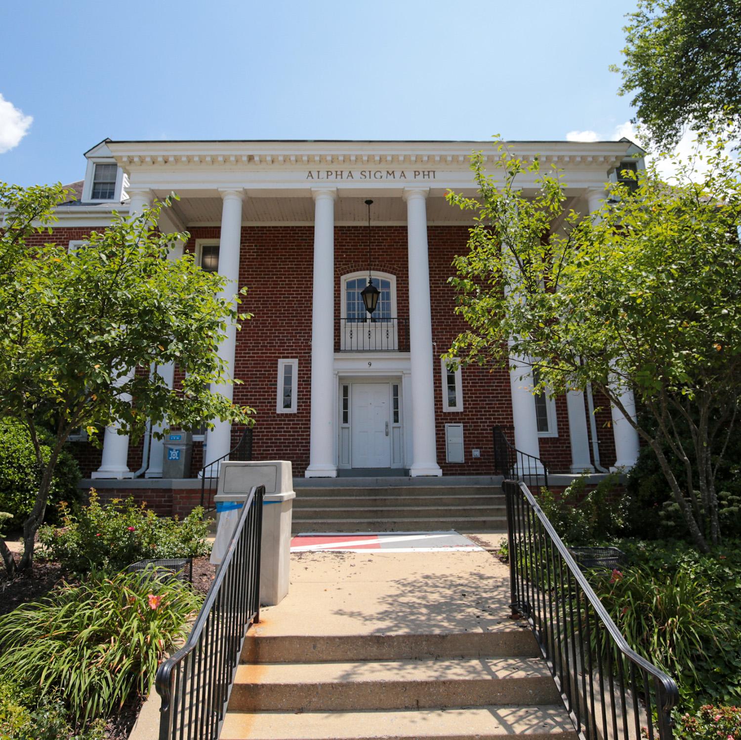 Brick house at 9 Fraternity Row with white columns and surrounding greenery