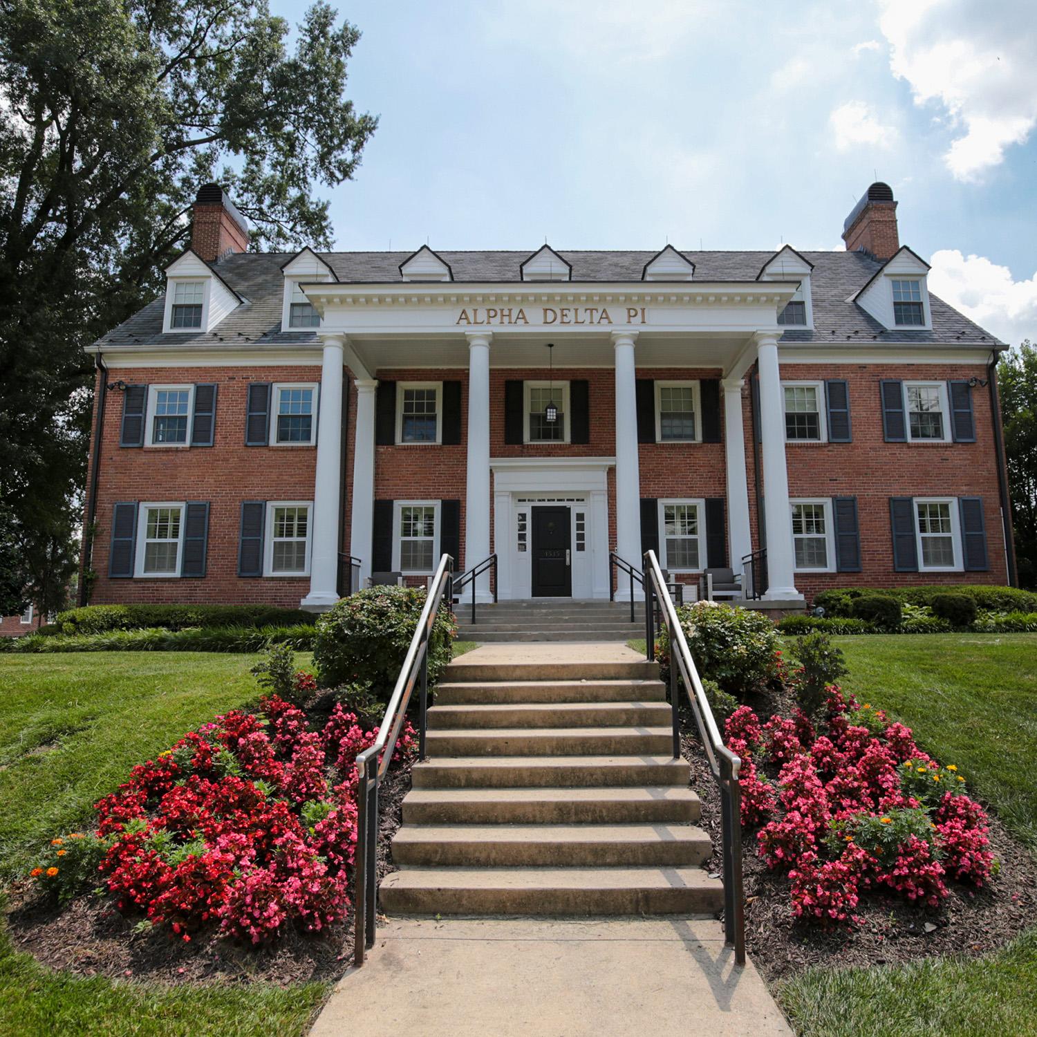 Brick house at 4535 College Avenue with window shutters, white columns, and a front entrance framed by surrounding greenery